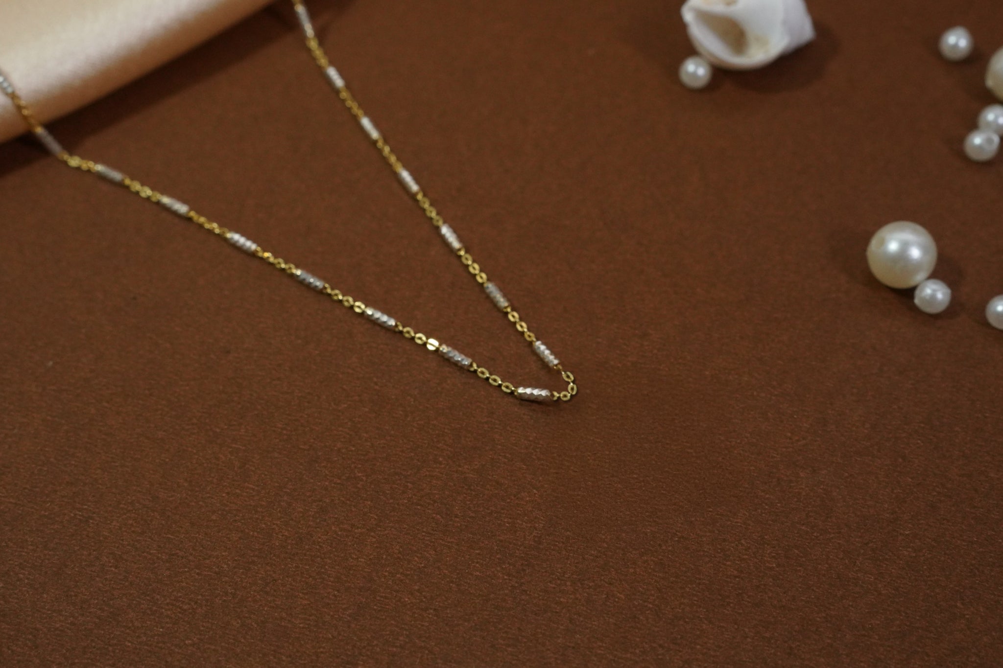 Satellite chain necklace with gold-toned links and evenly spaced machine-cut rhodium accents, offering subtle shimmer and versatile layering for daily wear and evening outings.