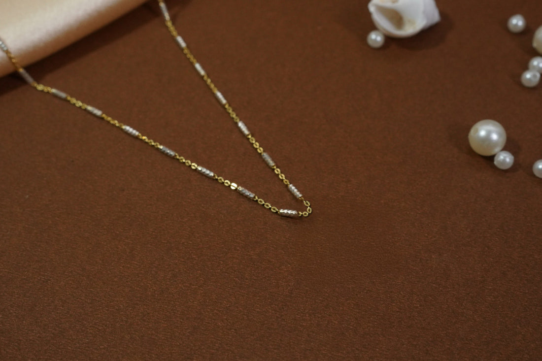 Satellite chain necklace with gold-toned links and evenly spaced machine-cut rhodium accents, offering subtle shimmer and versatile layering for daily wear and evening outings.