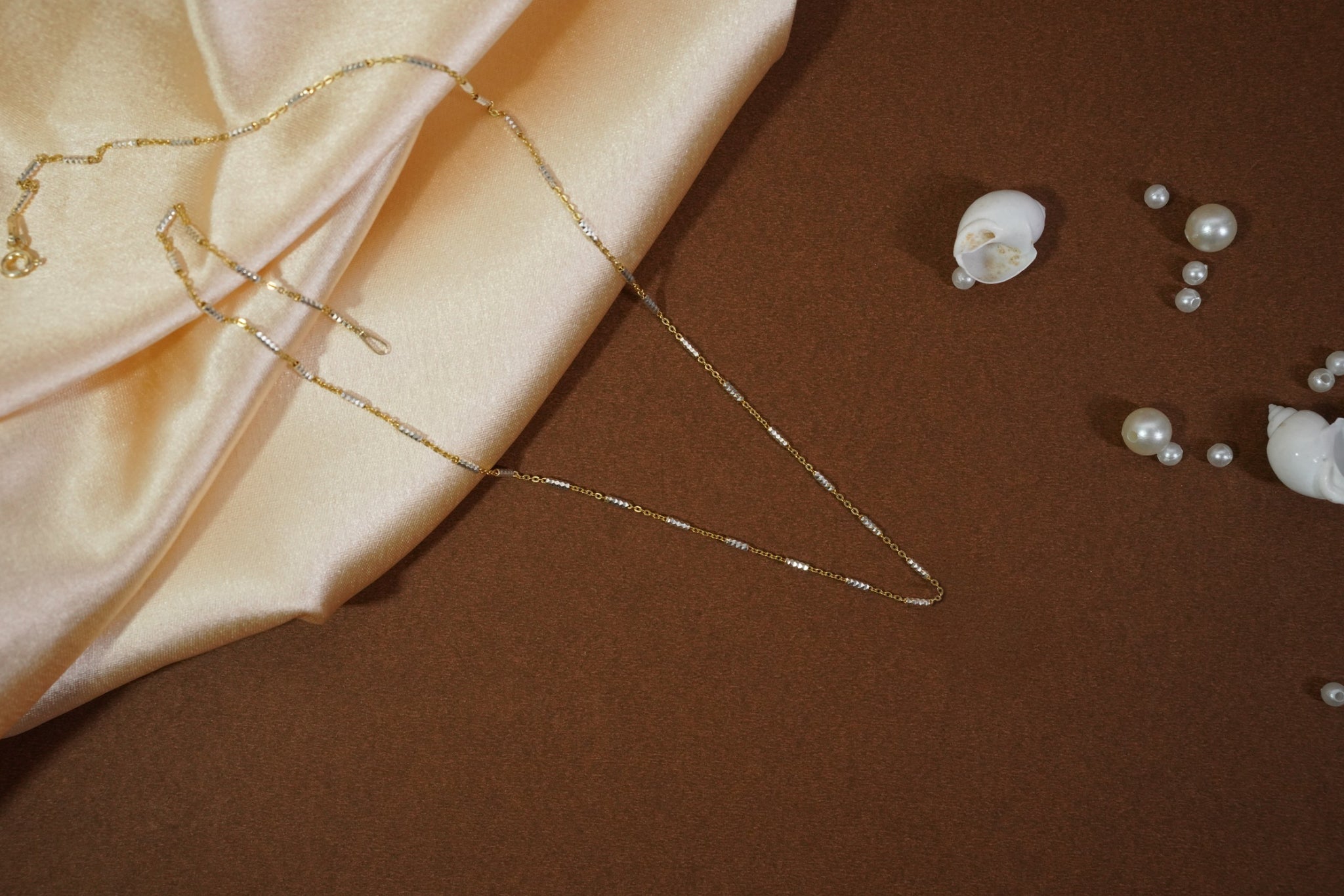 Satellite chain necklace with gold-toned links and evenly spaced machine-cut rhodium accents, offering subtle shimmer and versatile layering for daily wear and evening outings.