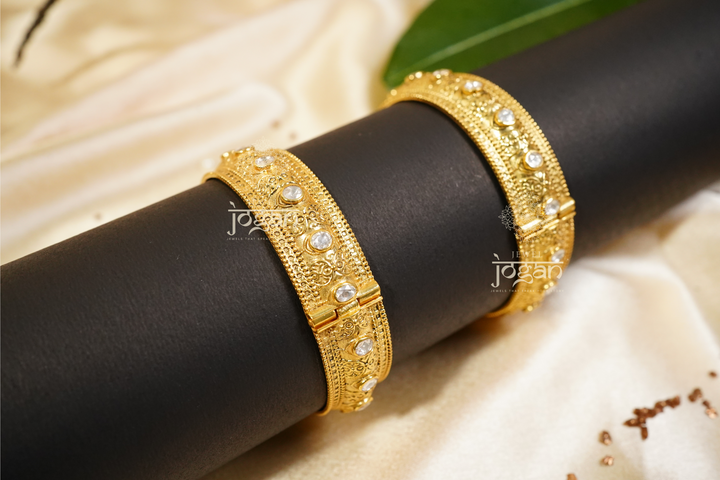 Intricate gold-plated Suvarnaa Kadaa with shimmering lab-grown Polkis, featuring a wide, ornate design. These traditional Indian bangles are perfect for cultural events, weddings, and festive occasions like Diwali or Eid. The elegant filigree work and radiant stones appeal to those seeking authentic, high-quality Indian jewelry with a touch of modern luxury. Suitable for women of all ages and a great gift option.
